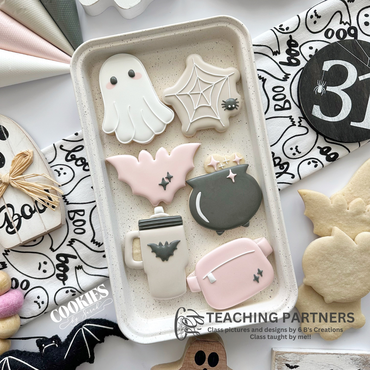 Six pink, cream and charcoal Halloween cookies featuring a ghost, spiderweb, bat, cauldron, tumbler and belt bag for a Cookies by Sarah decorating class in South Tampa.